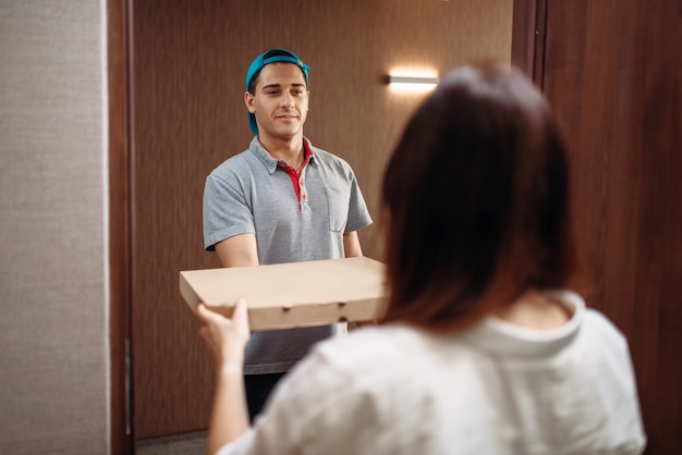 Entregador de pizza dá caixa para cliente