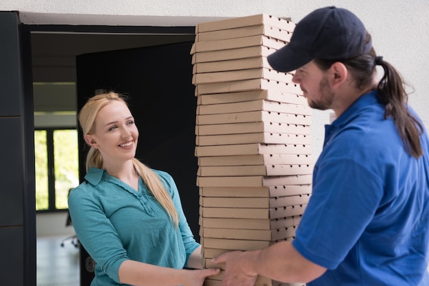 Entregador de pizza dando caixas de pizza para mulher jovem sorridente