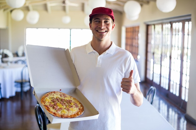 Entregador de pizza, mostrando pizza fresca e polegares para cima