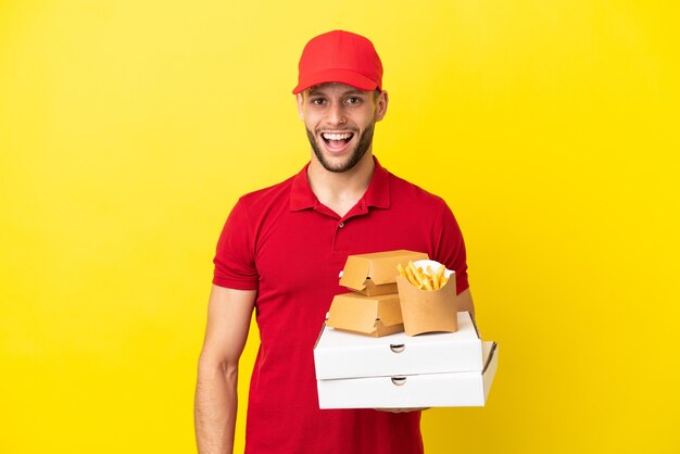 Entregador de pizza pegando caixas de pizza e hambúrgueres sobre um fundo isolado com expressão facial de surpresa