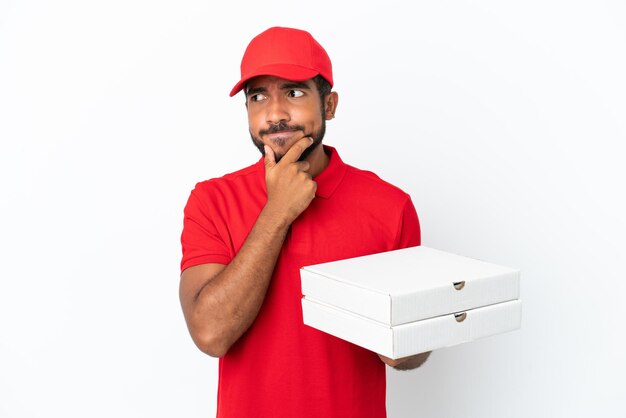 Entregador de pizza pegando caixas de pizza isoladas no fundo branco, tendo dúvidas e pensando