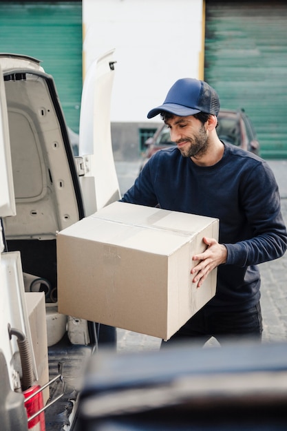 Entregador, descarregando a caixa de papelão do veículo