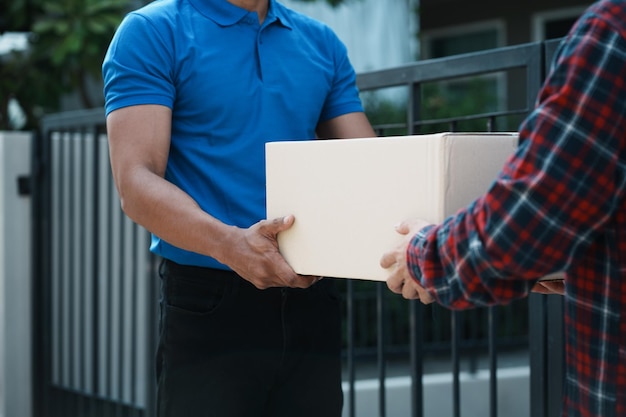 Foto entregador entregando caixa de encomendas ao cliente em pé na frente da casa