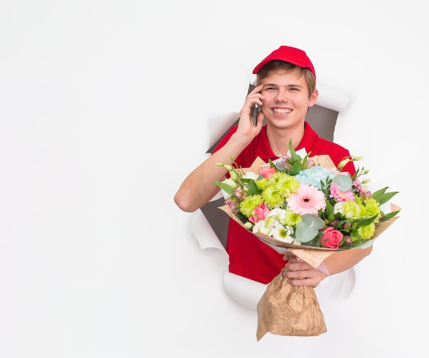 Entregador feliz com flores e smartphone no espaço de cópia de fundo branco Entrega expressa