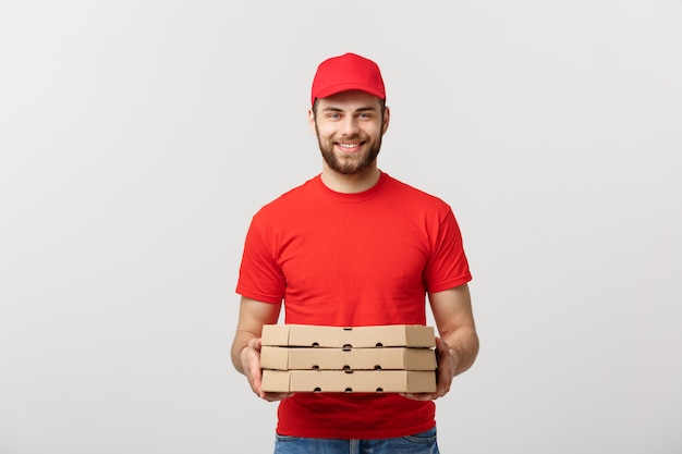 Entregador jovem alegre segurando caixas de pizza enquanto isolado no fundo branco do estúdio