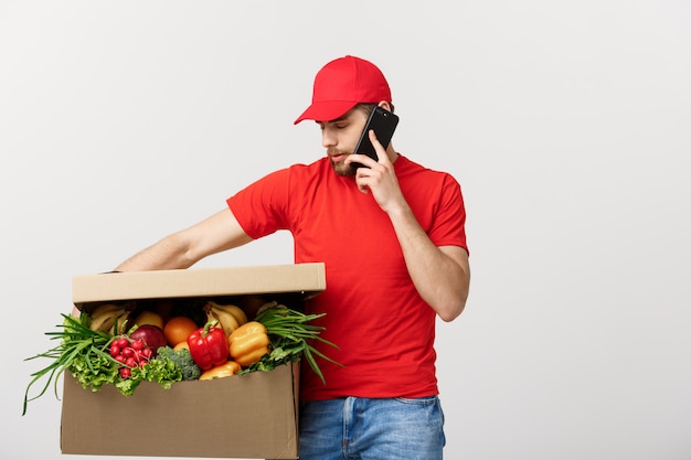 Entregador segurando a caixa de papel com comida e fazer uma chamada com o telefone móvel