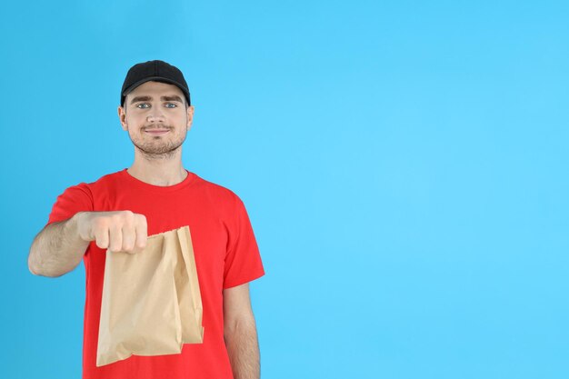 Entregador segurando sacolas de papel em fundo azul