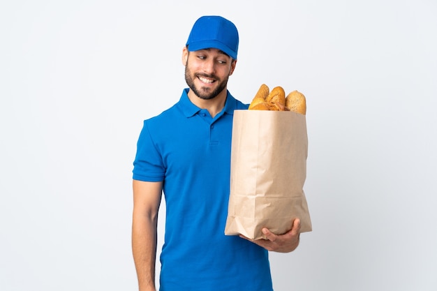 Entregador segurando uma sacola cheia de pães com expressão feliz