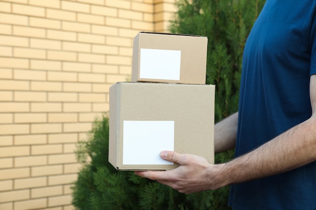 Foto entregador segurar caixas em branco ao ar livre, espaço para texto