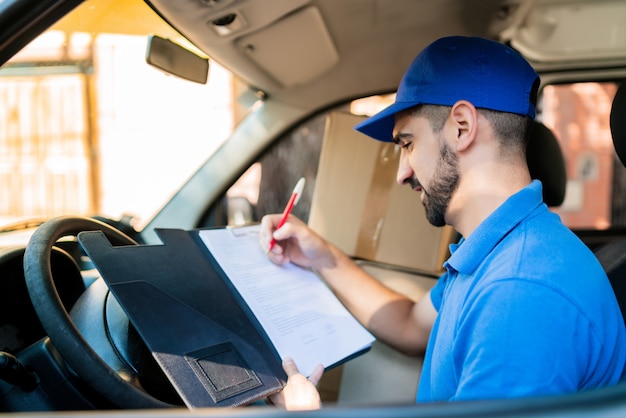 Foto entregador, verificando a lista de entrega na van