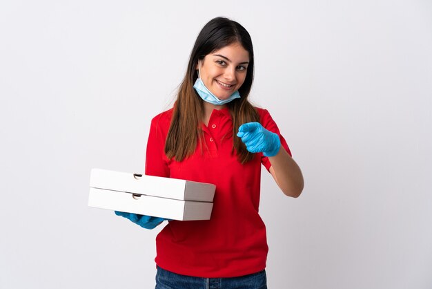 Entregadora de pizza segurando uma pizza isolada no fundo branco aponta o dedo para você com uma expressão confiante