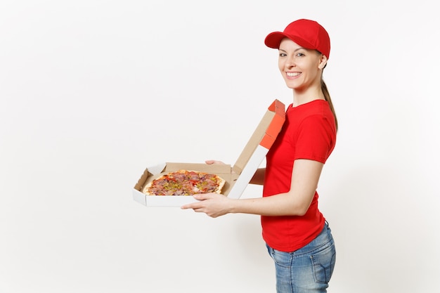 Foto entregadora de uniforme vermelho, isolado no fundo branco. linda mulher de boné, camiseta, jeans, trabalhando como mensageiro ou revendedor, segurando pizza italiana em uma caixa plana de papelão. copie o espaço para anúncio.