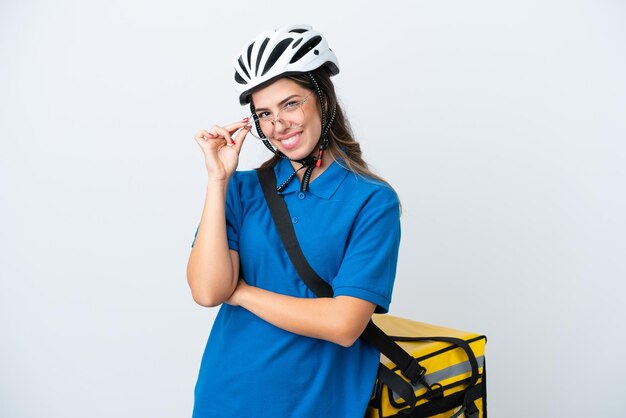 Entregadora jovem com mochila térmica isolada em fundo branco com óculos e feliz