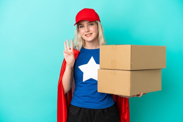 Entregadora, super-heroína, caucasiana, isolada em um fundo azul, feliz e contando três com os dedos