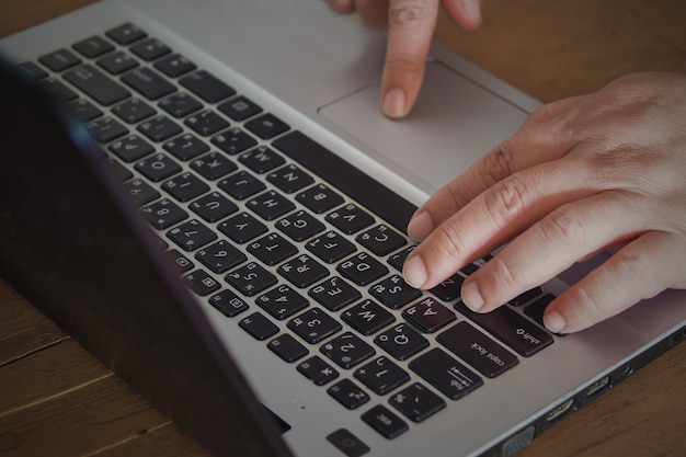 Entregue a datilografia no teclado do portátil, conceito em linha da compra.