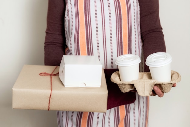 Entregue con cajas de papel y recipiente para llevar con dos tazas de café blanco.