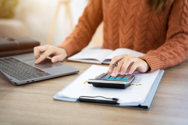 Foto entregue a las mujeres que hacen finanzas y calcule en el escritorio el costo en la oficina en casa