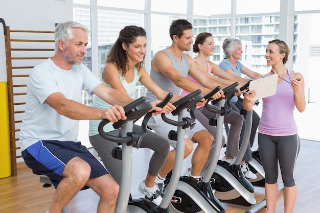 Entrenador además de personas trabajando en la clase de spinning