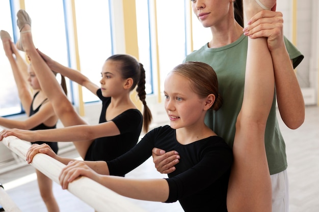 Foto entrenador de ballet femenino enseñando a las niñas en el gimnasio