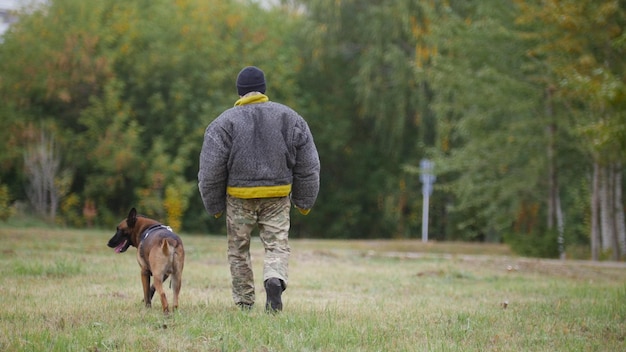 Un entrenador caminando con su perro pastor alemán entrenado