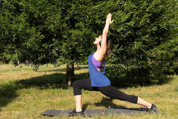 Entrenador, chica fitness femenino haciendo ejercicios en un parque verde.