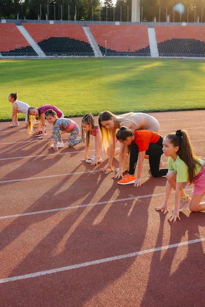 Foto un entrenador enseña a un gran grupo de chicas al principio antes de correr en el estadio durante la puesta de sol un estilo de vida saludable