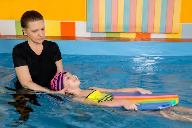 Entrenador enseñando a un niño en la piscina cubierta a nadar y bucear. Concepto de formación