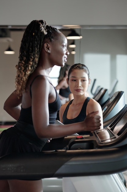 Entrenador de fitness controlando a su clienta corriendo en cinta antes de hacer ejercicio