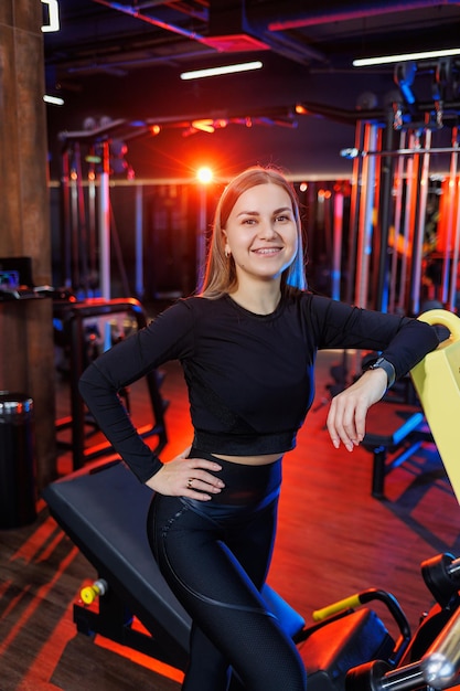 Un entrenador de fitness experimentado de una mujer deportiva se encuentra en el gimnasio y piensa en un plan de ejercicios. Concepto de dieta y pérdida de peso. Entrenadores personales mujeres en el gimnasio.