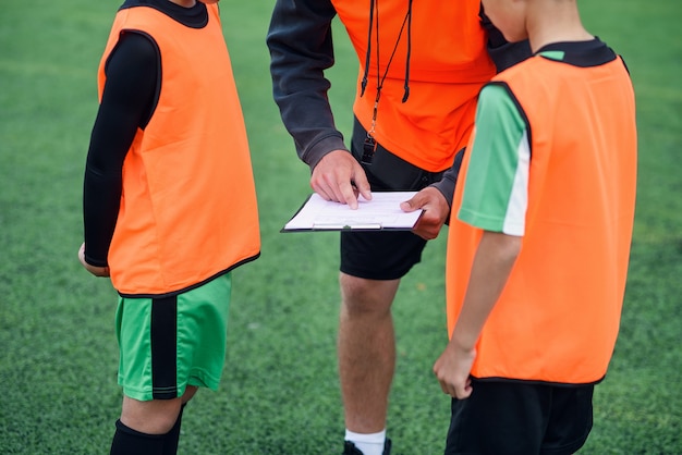 Entrenador de fútbol joven profesional cuenta la estrategia del juego de fútbol a sus jugadores