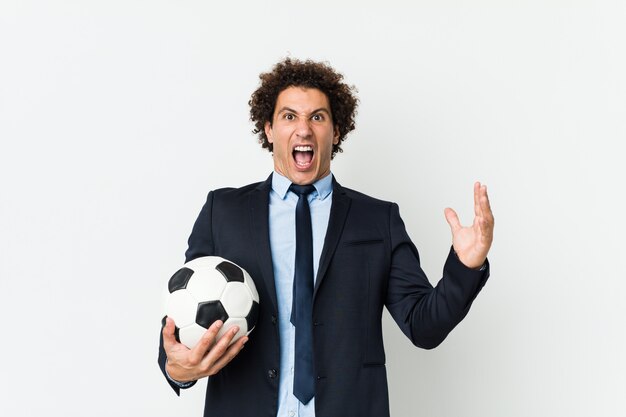 Entrenador de fútbol sosteniendo una pelota celebrando una victoria o éxito