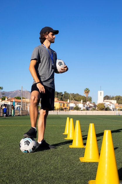 Entrenador de fútbol de tiro completo ayudando a los niños