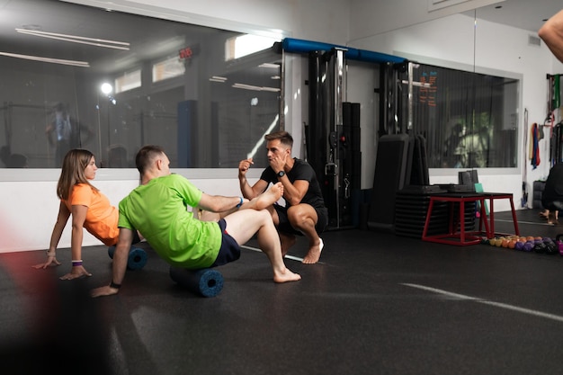 Un entrenador guiando a dos de sus alumnos en el gimnasio.