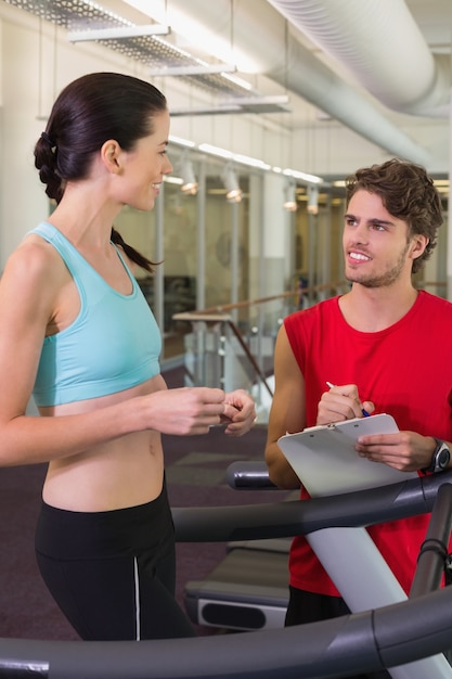 Entrenador hablando con su cliente en la cinta de correr