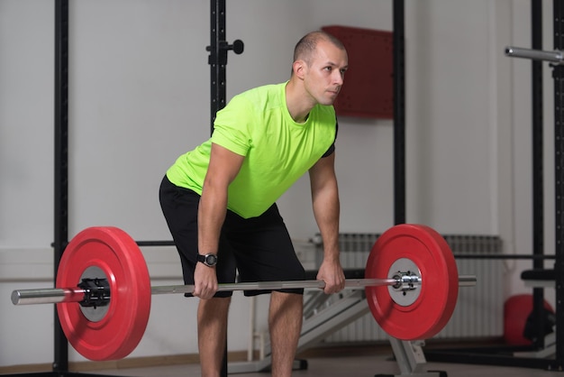 Entrenador haciendo ejercicio de peso pesado para la espalda con pesas en el gimnasio