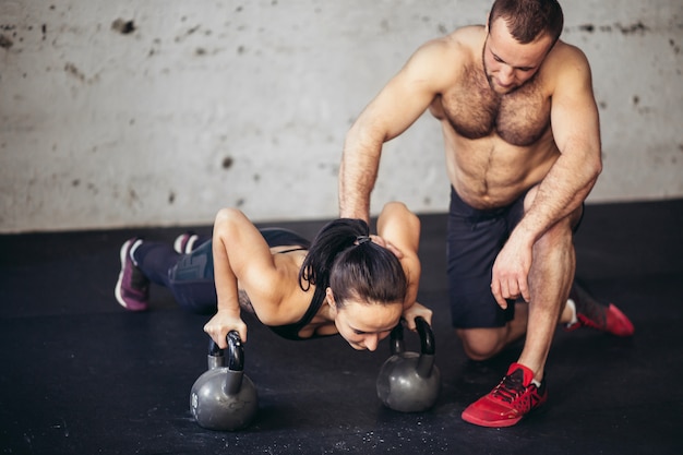 Entrenador hombre y mujer push-up fuerza pushup en un entrenamiento físico