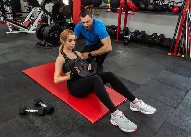 Entrenador masculino de fitness con su cliente trabajando haciendo ejercicio en el gimnasio Entrenamiento de concepto de energía