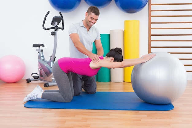 Foto entrenador con mujer en ejercicio de pelota