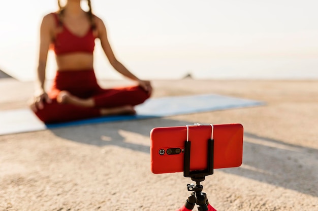 Foto entrenador de mujer joven en forma deportiva haciendo yoga al aire libre