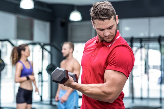 Entrenador muscular levantando una pesa