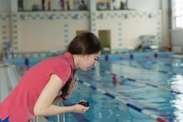 Entrenador de natación mirando el cronómetro cerca de la piscina en el centro de ocio.