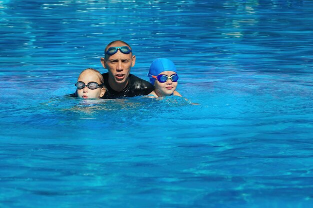 El entrenador de natación realiza una lección individual con la niña en la piscina al aire libre.