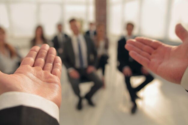 Entrenador de negocios La vista trasera de un hombre gesticulando con la mano mientras se enfrenta a un grupo de personas desenfocado