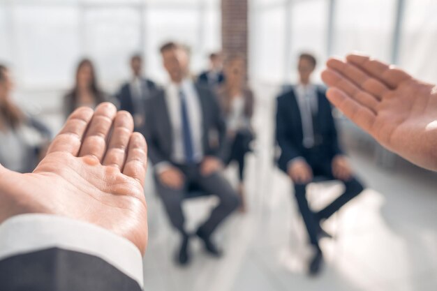 Entrenador de negocios La vista trasera de un hombre gesticulando con la mano mientras se enfrenta a un grupo de personas desenfocado