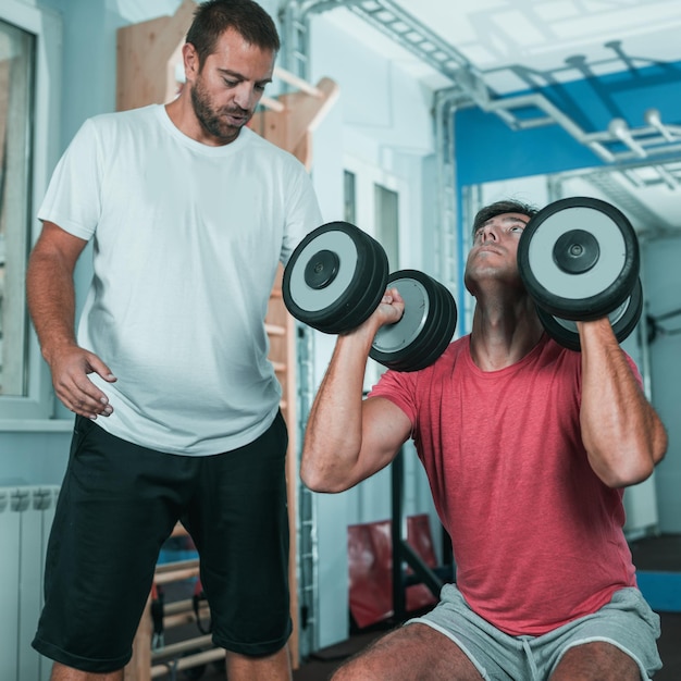 Entrenador peronal con cliente masculino en el gimnasio.