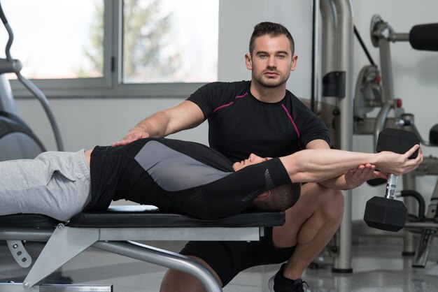 Entrenador personal ayudando al cliente en el gimnasio