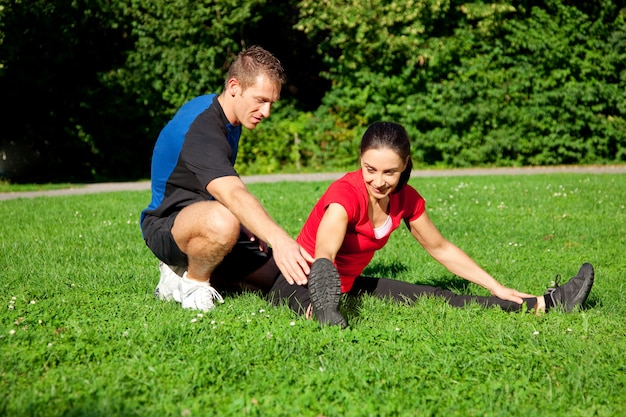 Entrenador personal ayudando a mujeres con deporte al aire libre.