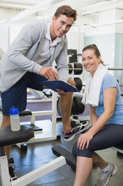 Entrenador personal y cliente mirando juntos portapapeles