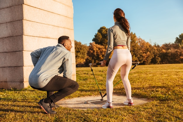 Foto entrenador personal entrenando a una chica fuera