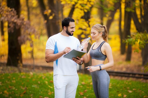 Entrenador Personal Fitness Toma Notas Mientras Mujer Hace Ejercicio Aire Libre